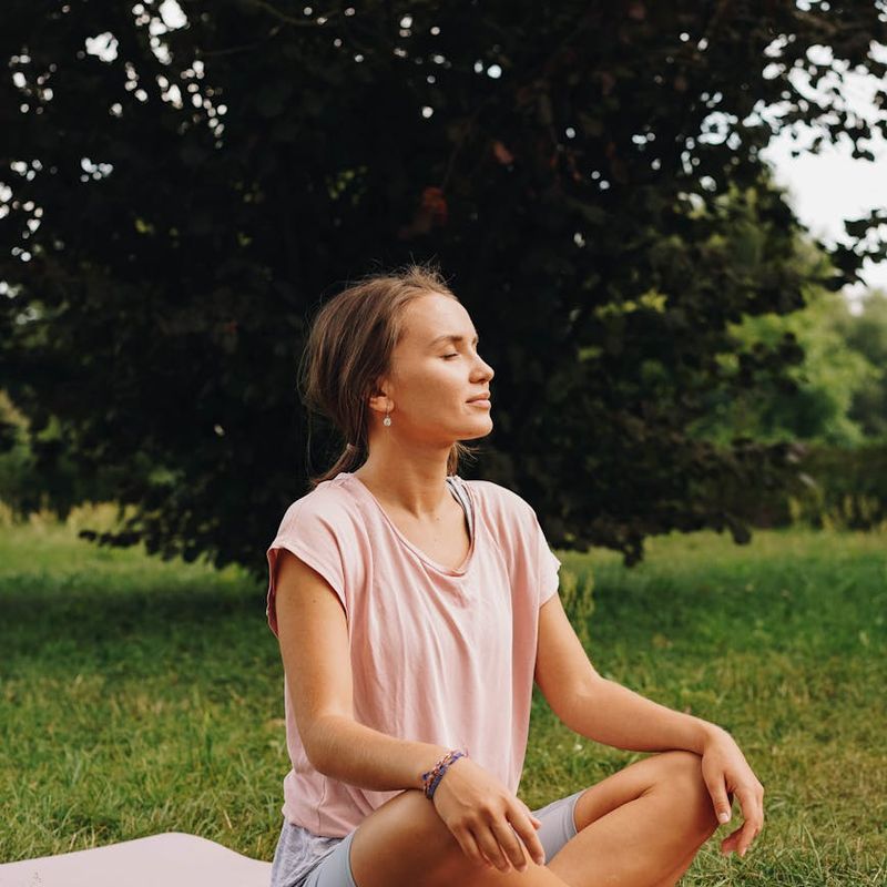 Person sitting in a meditative yoga pose with eyes closed, looking calm and focused.